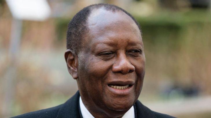 Alassane Ouattara smiles, wearing a dark jacket and a white shirt.