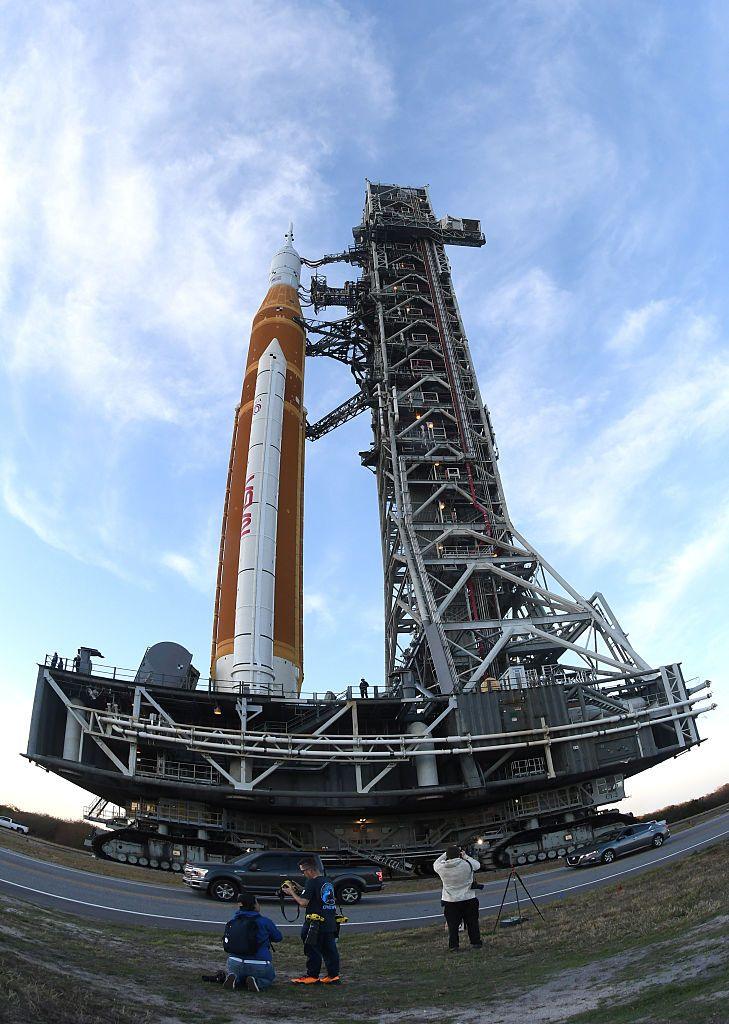 A fish eye lens perspective looking up at Artemis II Space Launch System (SLS) rocket as it's rolled back from pad 39B to the Vehicle Assembly Building.