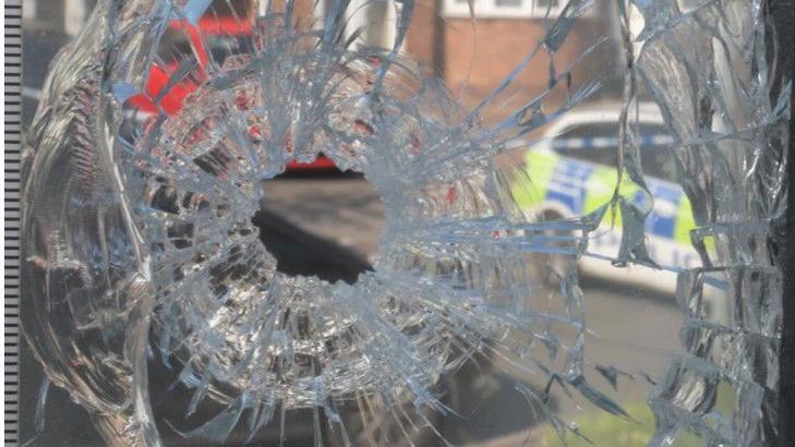 A close up of a window, shattered due to a gunshot 