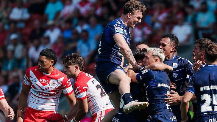 Toulouse players, in dark blue, celebrate a try against St Helens, two of whose players, in red and white, look disconsolate.