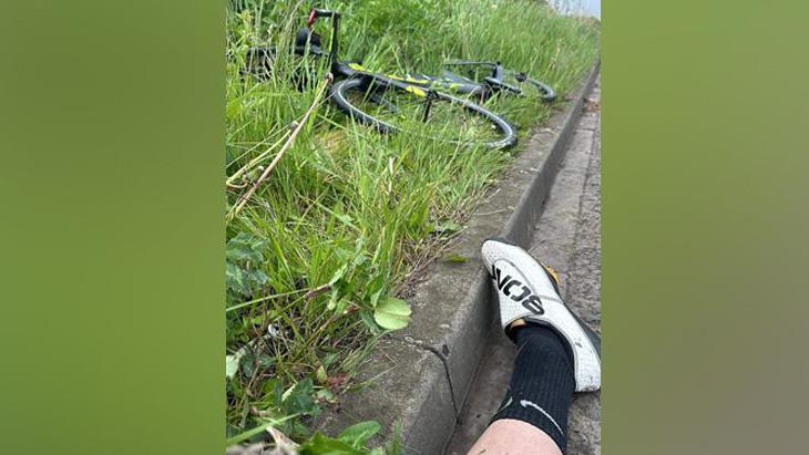 An image of a foot with a bike in the grass on the verge