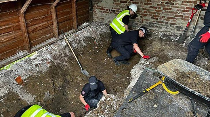 Officers digging a trench inside a barn