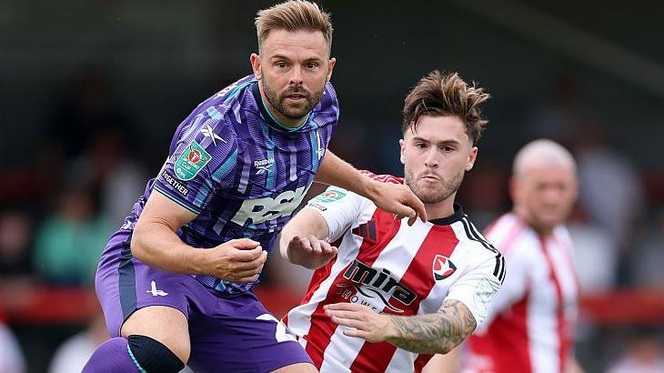 Matthew Godden (left), of Charlton Athletic, battles for the ball with Cheltenham Town's Charlie McCann