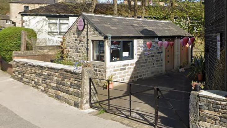 Picture of a small stone building next to a road