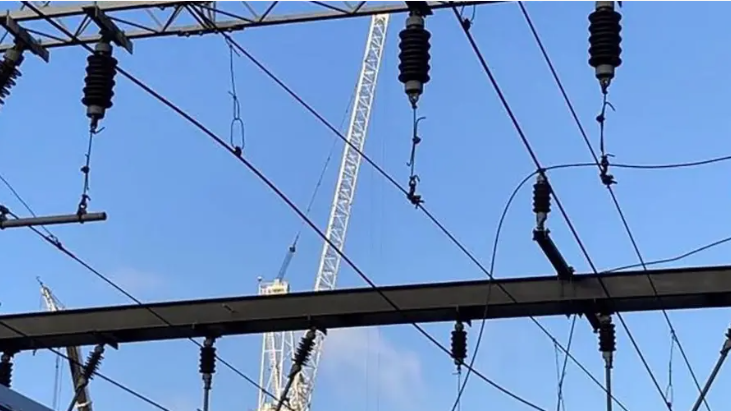 Overhead rail lines and gantries in front of a clear blue sky.