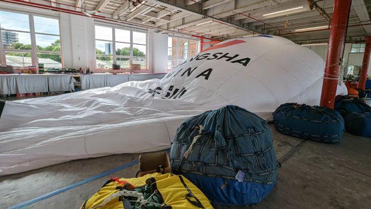 The Changsha balloon, partly inflated in a warehouse. It has English and Chinese writing on it. 