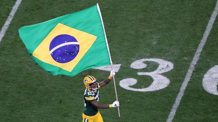 Jaire Alexander of the Green Bay Packers runs onto the field with a Brazilian flag before the game against the Philadelphia Eagles in Sau Paulo