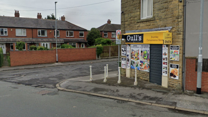 Street view showing a yellow corner shop called "Gull's". A residential street is in the background.