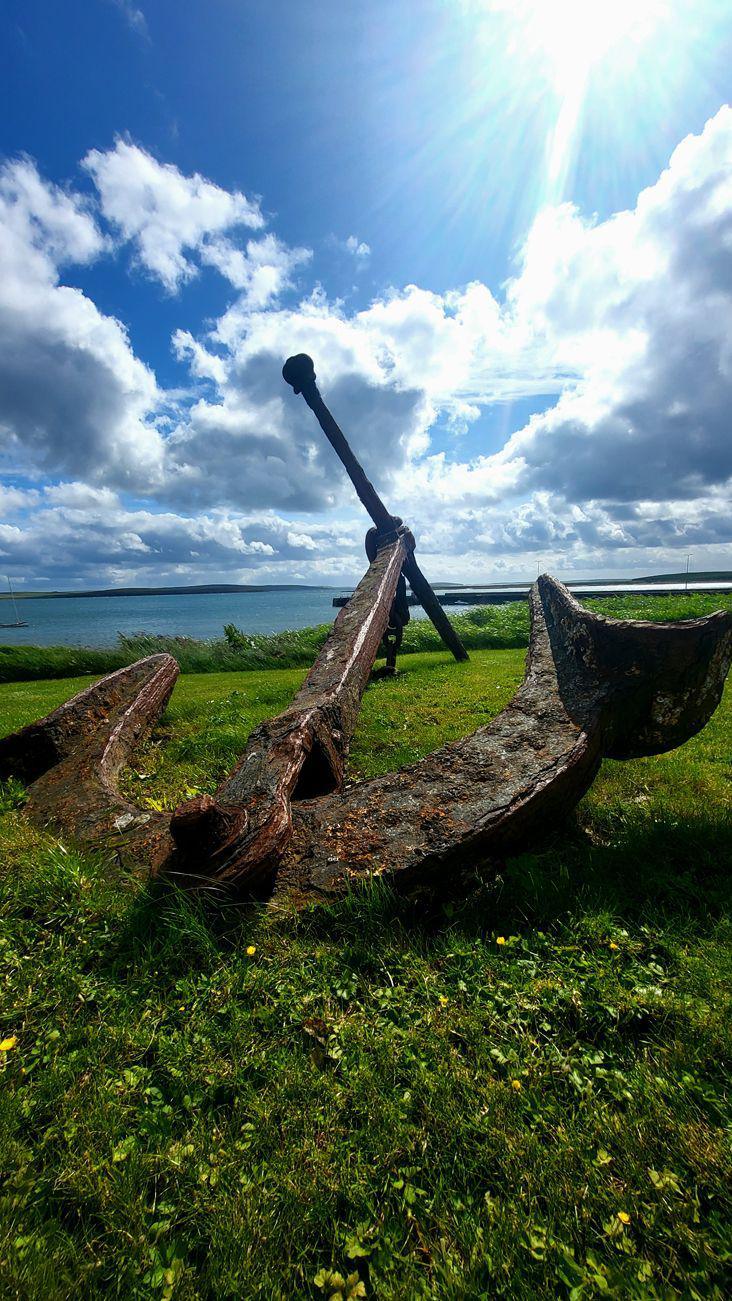 An old anchor against a skyline with sun breaking through the clouds