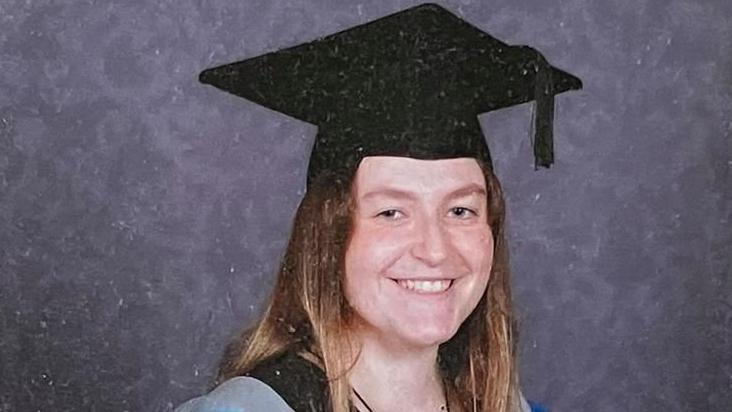Beth Yates wears a mortarboard and robes on her graduation day from the University of Exeter.