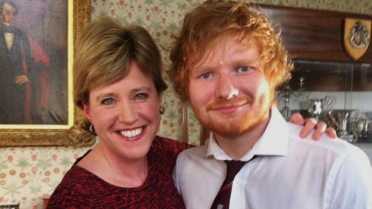 Susie Fowler-Watt, wearing a maroon and black coloured dress, pictured with Ed Sheeran, who is wearing a white shirt and maroon tie