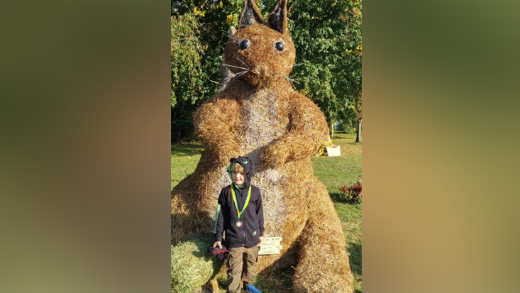 Squirrel scarecrow with a little boy standing in front