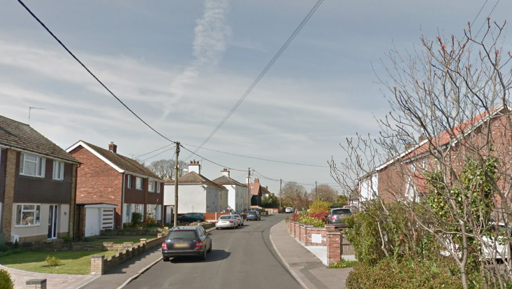 A general view of Manor Road. Houses line the side of the road with vehicles parked up on the left hand side. Electricity cables travel over the road.