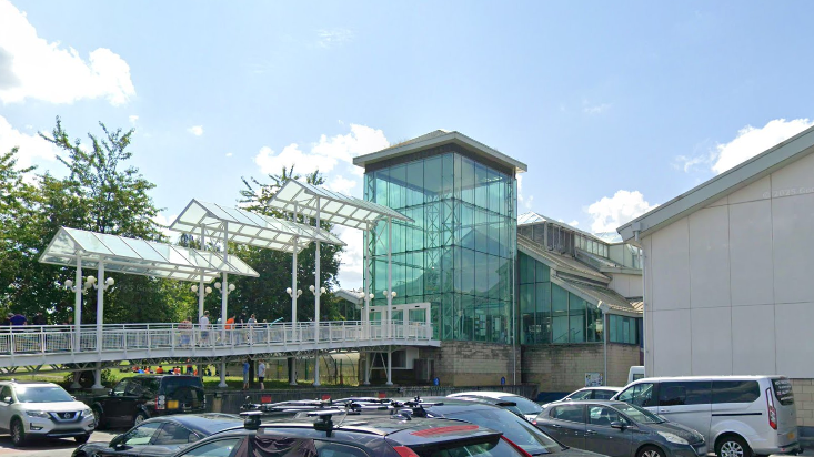The entrance of Guildford Spectrum. A walkway leads up to the entrance, which is a rectangular green glass building.