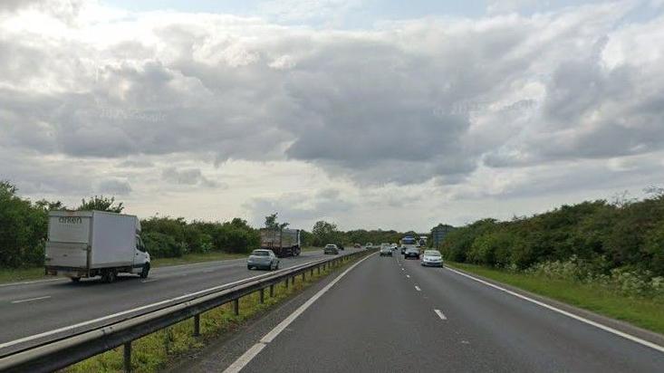 View of part of the A14. It is a dual carriageway road and cars and lorries are driving along both sides.
