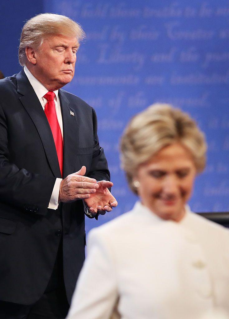 Hillary Clinton walks off stage as Donald Trump applauds during a debate.