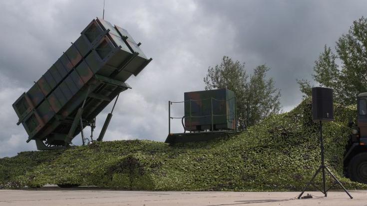 A Patriot system received by Ukraine is seen on the Day of Ukrainian Air Force on August 4, 2024 in Ukraine. The camouflage-painted rectangular system is raised at an angle on a platform on top of a grassy mound.