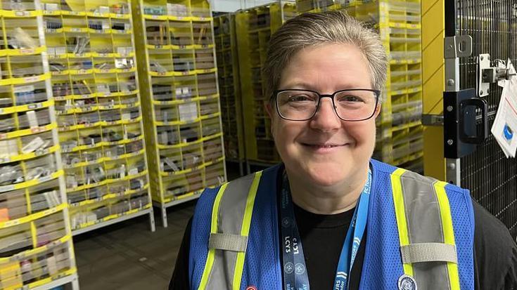Amazon Tour Leader Angie White with back to warehouse area in the Dartford LCY3 site.