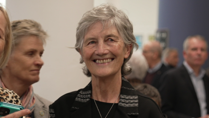 Connolly has short grey hair and is smiling in the picture as she wears a black top and jacket.