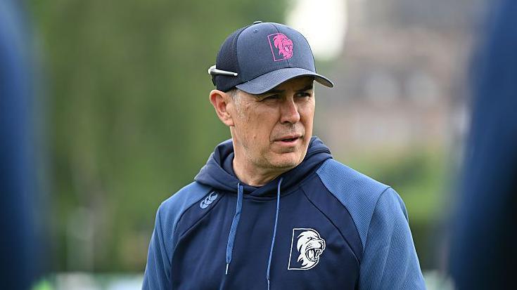 Ryan Campbell wearing a Durham two-tone blue hoodie and a Durham cap with sunglasses on the back of his cap