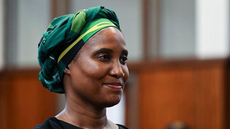 Duduzile Zuma-Sambudla is seen wearing a green and yellow headscarf and black dress as she appears in court