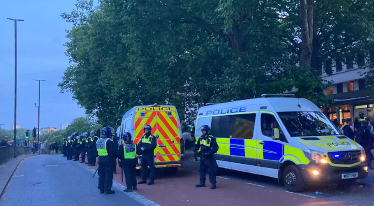 Police officers in riot gear and vans line up outside the Mercure Hotel in Bristol during unrest involving far-right protesters on 3 August