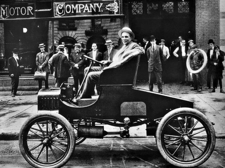 Henry Ford, US car manufacturer, poses in his new T Ford model in front of his car plant in Detroit in the early 1900s