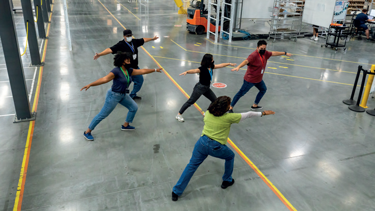 Five people taking part in an exercise class on a factory floor