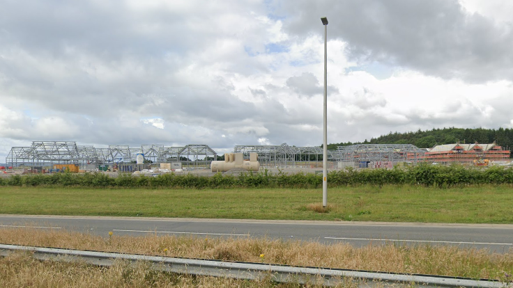 A construction site with iron frames, seen from the other side of a dual carriageway