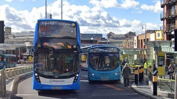 A double decker bus and a single decker bus on a road at traffic lights 