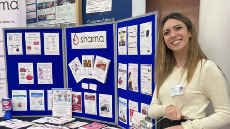 A woman wearing a white jumper stood next to a fundraising table