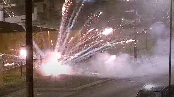 A firework going off in the street, with sparks and plumes of smoke rising