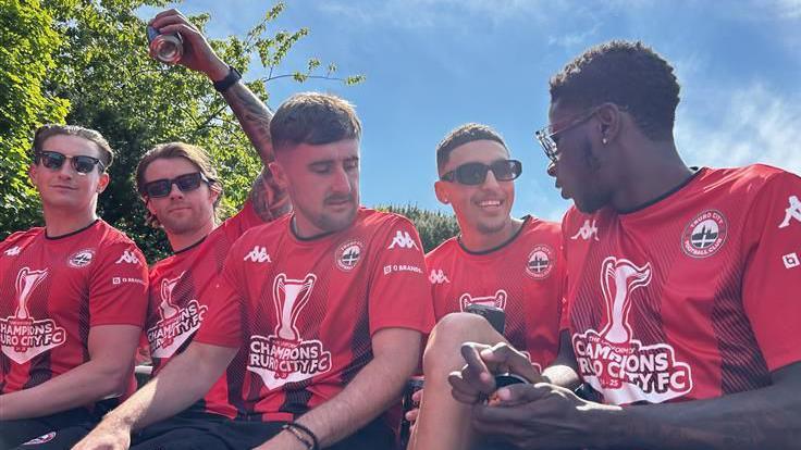 Five of the players sitting on the bus in their kit