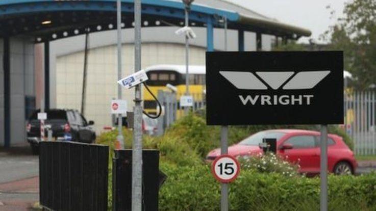 Entrance to Wrightbus factory in Ballymena where a sign in black and silver that says 'WRIGHT' and behinf it is a blue archway into the main factory