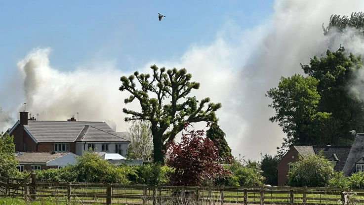 Large plumes of smoke above houses and gardens