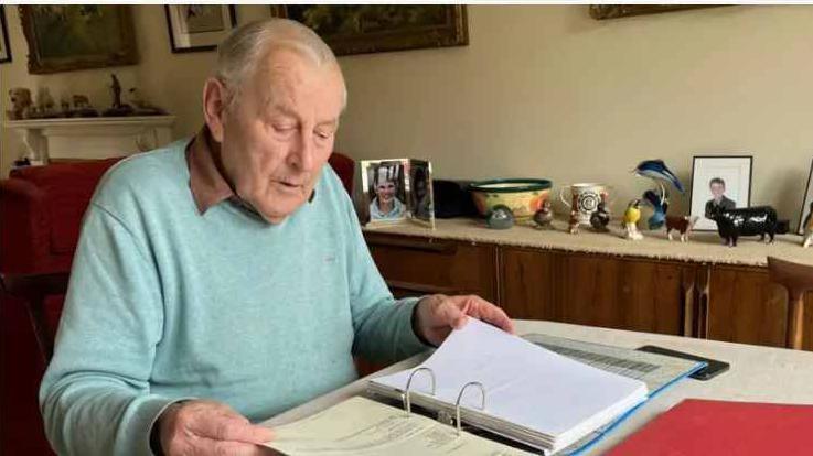 Peter Walker sits at home, working at his dining room table surrounded by files from his campaign.