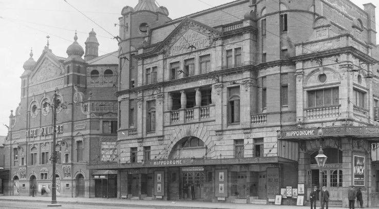 A grainy black and white image of the old Hippodrome Theatre next to Belfast Grand Opera House. The building is highly detailed with many different sized windows, balconies and verandas. 