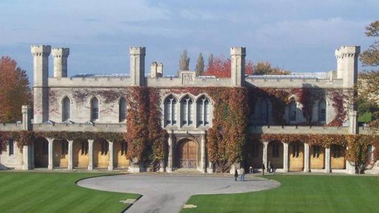 Lincoln Crown Court, a Victorian Gothic two-storey stone building with pillars and four large towers. Covered in green ivy around the doorway, with a lawn to the front.
