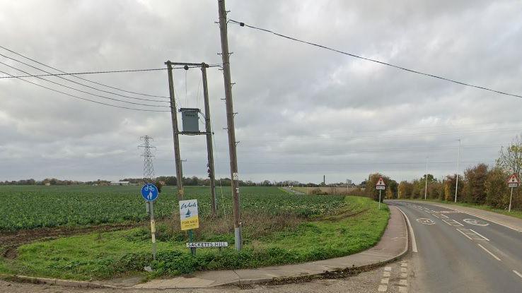 The junction of Sacketts Hill with the A255 with a field in the background and telephone poles in shot