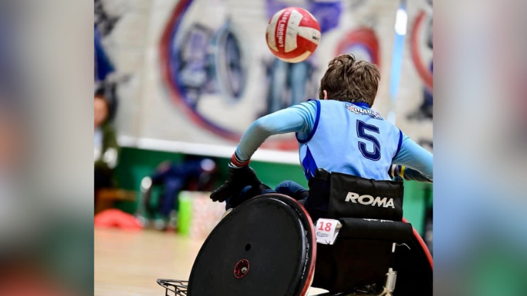 Phoebe Gibbons on the court at a recent league game. She is facing away from the camera. A ball is seen in the air.