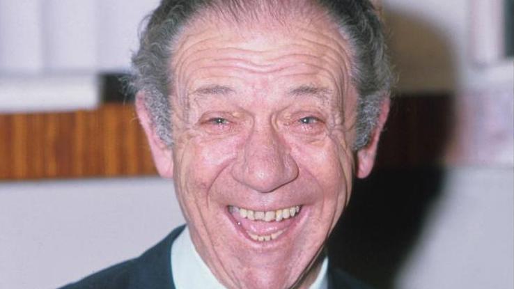 Sid James, who has grey hair, smiling broadly