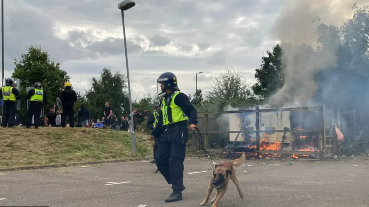 A police officer and a dog attending a racially-motivated riot at the Holiday Inn Express in Manvers, Rotherham 