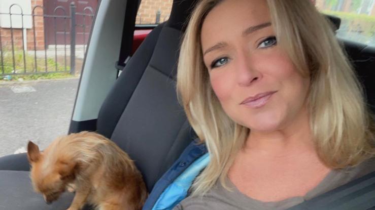 Teresa McMahon sitting in a car with a small dog sitting on the seat next to her