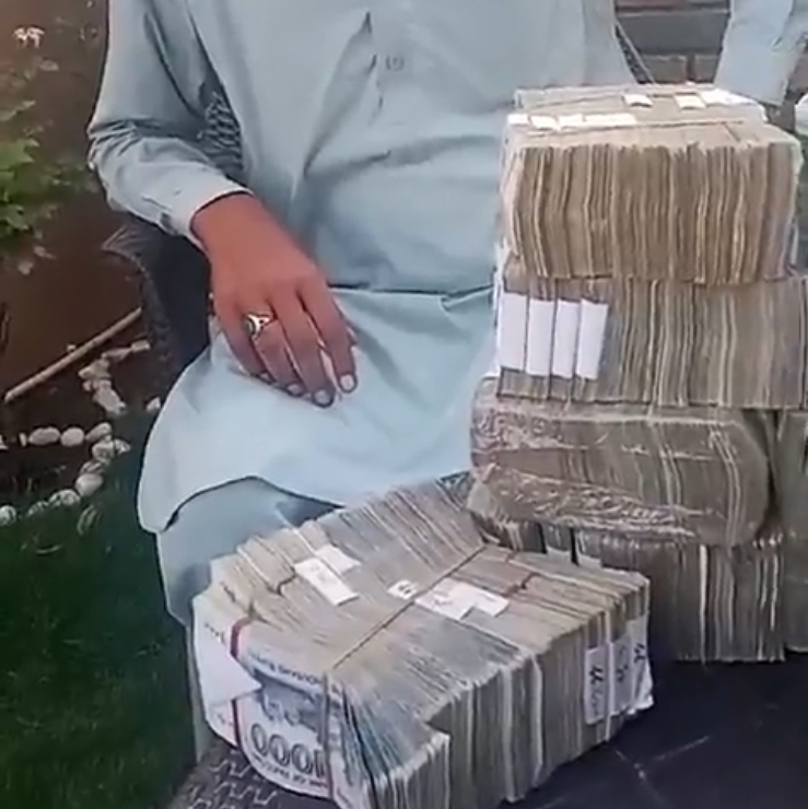 A man sitting behind a huge was of banknotes