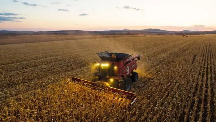 An aerial shot of a farm vehicle ploughing a large field