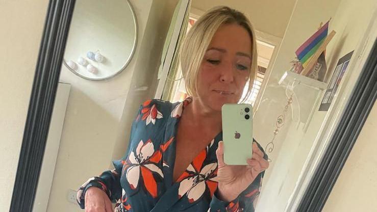 Teresa McMahon wearing a floral dress and taking a selfie in a mirror.