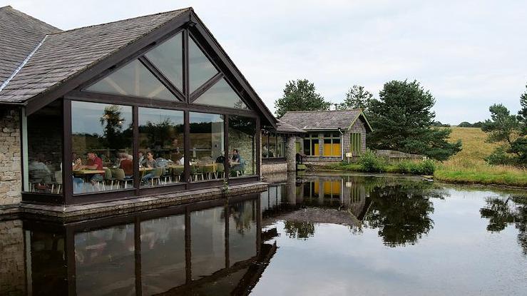 Image shows people sitting in the window of the cafe at Tebay services, which look out over the pond 