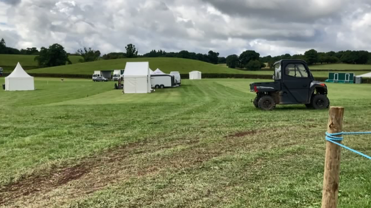 A farm vehicle in a field with tents