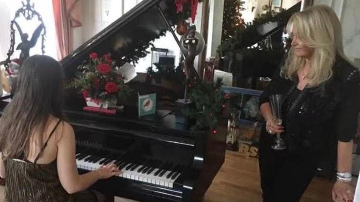 Llun o merch yn chwarae piano a Bonnie Tyler yn sefyll wrth ei hochr. 