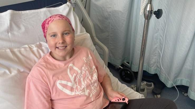 Eve Shipley receiving hospital treatment. She is wearing a pink shirt with a white heart and white lettering over the top. She has a pink scarf over the top of her head.